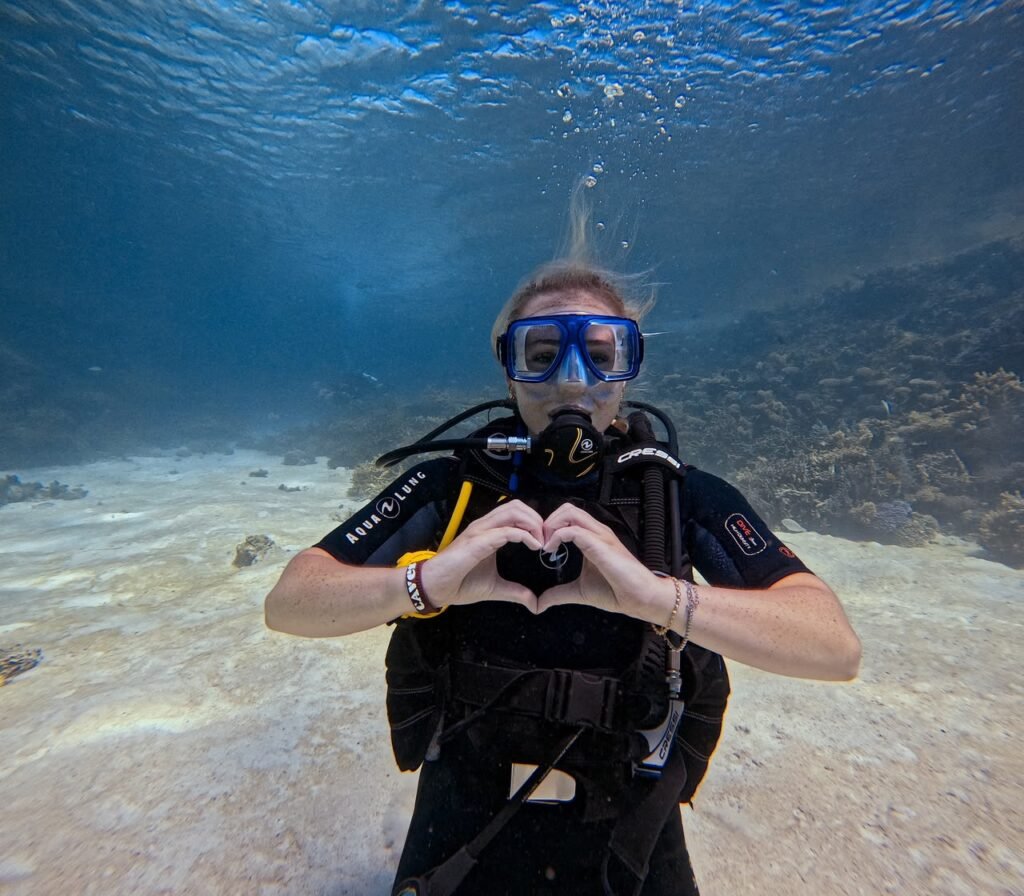 Smiling diver making a heart shape with their hands